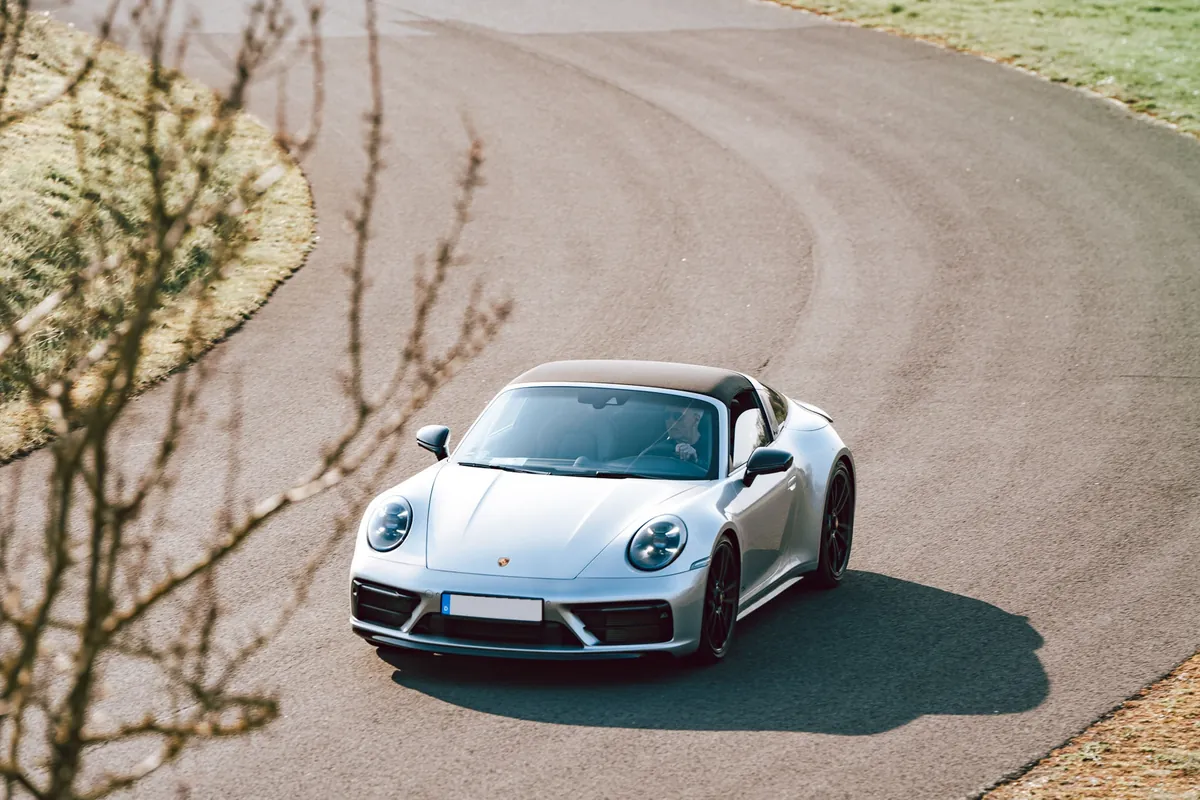 Silbergrauer Porsche 911 Targa fährt durch eine Kurve, von schräg oben fotografiert – Eventfotografie bei der Precision Drive Experience von Sportwagen Werk